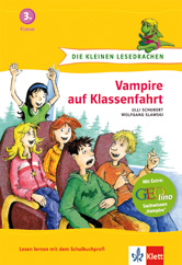 Fünf animierte Kinder sitzen zusammen und wirken überrascht und aufgeregt, mit einer grünen Drachenillustration am oberen Rand. Auf dem Buchdeckel steht Vampire auf Klassenfahrt.